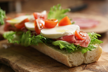 open sandwich with prosciutto, mozzarella and tomatoes on kitchen table, shallow focus