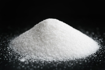 heap of extra small salt on black background, shallow focus