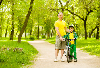 Obraz premium old man teaching his grandson to ride a bike
