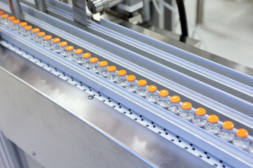 Sterile capsules for injection. Bottles on the bottling line of the pharmaceutical plant. Machine...