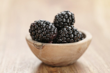 fresh blackberry in wooden bowl on table closeup, with copy space