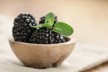 fresh blackberry with mint leaves in wooden bowl on table closeup, with copy space