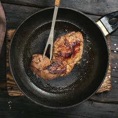 Beef steak in a pan on a dark wooden table