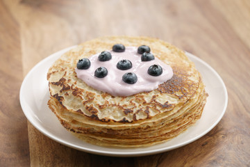 blini or crepes with yogurt and blueberries on wood table, sweet breakfast
