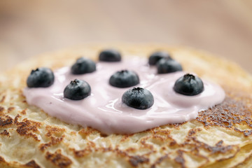 blini or crepes with yogurt and blueberries closeup, sweet breakfast