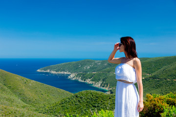 beautiful young woman standing on the wonderful mountains and sea background in greece