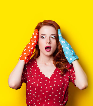 beautiful surprised young woman with colorful potholders on the wonderful yellow background
