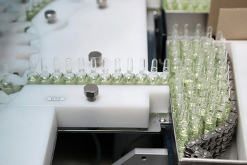 Sterile capsules for injection. Bottles on the bottling line of the pharmaceutical plant. Machine...