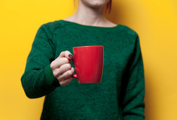 beautiful young woman hand holding a red cup of the wonderful yellow background