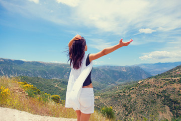 beautiful young woman standing in front of splendid mountain background in Greece