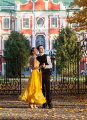 Pair of dancers dancing in the ..palace garden. Man with suit and woman in a yellow long dress  in...