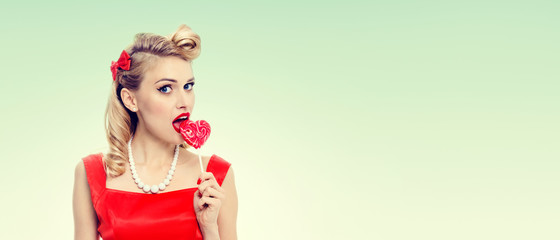 young woman eating colourful lollipop, dressed in pin-up style