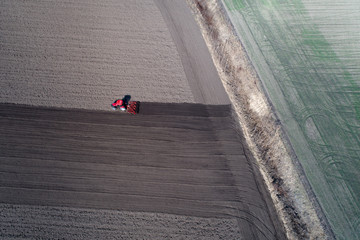 Aerial image of tractor harrowing soil in springtime shoot from drone
