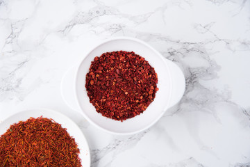 Top view of dried saffron and chilli pepper in bowls