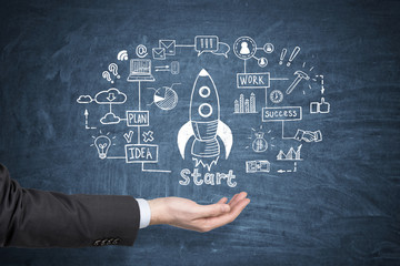 Man hand and rocket sketch on blue chalkboard