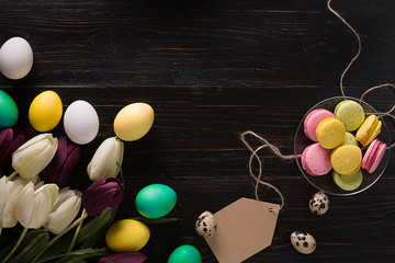 Obraz premium Easter eggs and tulips on dark wooden planks