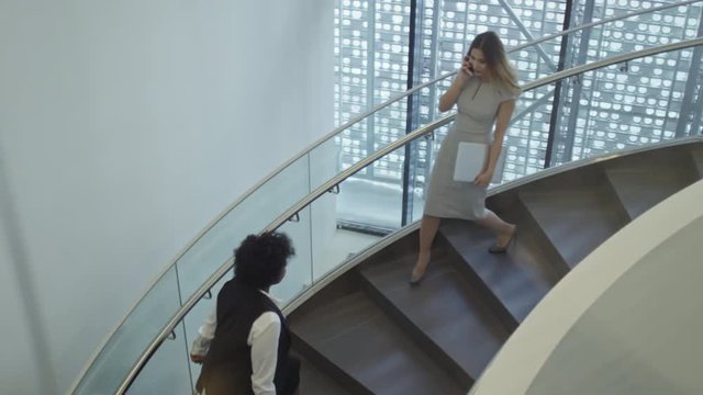 High angle view of businessmen and businesswomen walking up and down the stairs in office building