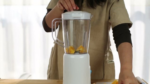 girl squeezing fresh orange for juice with juice extractor
