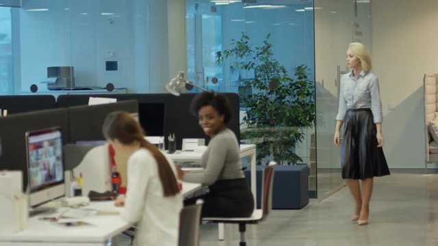 Tracking shot of business people working on computers in modern open-space office