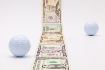 Strip of different us dollar banknotes and white golf ball