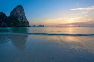 Rocks protruding from the sea and calm water surface at sunset.