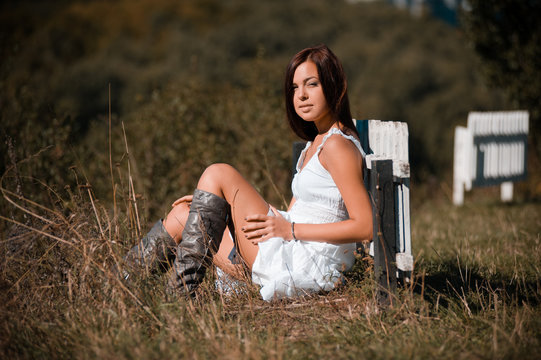 Portrait of a beautiful girl in a white dress and cowboy boots