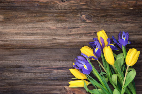 Bouquet of flowers. Yellow tulips and iris flowers over rustic wooden background. Table top view and copy space for text. Holidays, Easter, Mother's day background or card