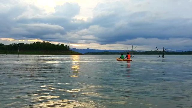 Family relax with kayak at sunrise on river with cloudy sky after rainy day