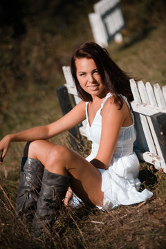 Portrait of a beautiful girl in a white dress and cowboy boots