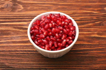 Bowl with pomegranate seeds on a wooden table