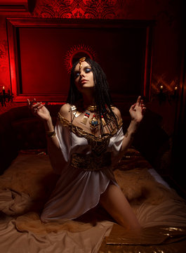 Young queen in the rich chambers. The girl is dressed in a Greek dress and gold jewelry with snakes and scarabs.