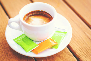 Coffee cup in a cafe, with three packets of sugar