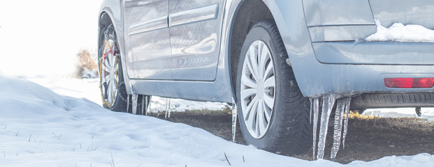 Huge icicles on the dirty car wheel. Dangerous ice build up car wheel fender arch. Driving...
