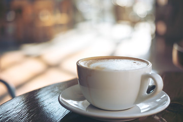 A cup of hot latte coffee on vintage wooden table in cafe