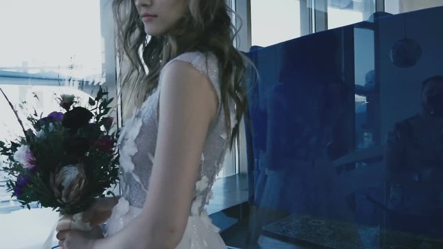 The bride in beautiful dress is rotated by the window in slow-motion