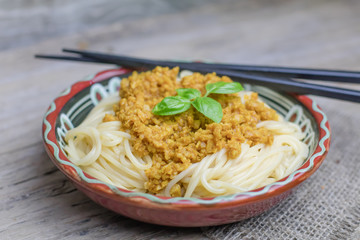 Soy vegan protein marinara spaghetti pasta in ceramic bowl with chopsticks on wooden background. Protein albumen source. Vegan vegetarian nutritional food.
