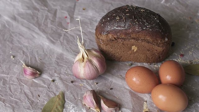 Black bread, eggs, and garlic on white background, close-up