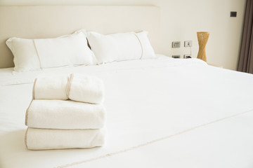 Clean folded towel are placed on the blanket on the bed with pillow  in the morning at bedroom