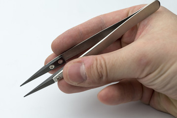 Hand holding a pair of tweezers.