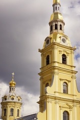Yellow tower with a bell tower and clock on a background of gloomy sky, Sightseeing of St. Petersburg - Peter and Paul Fortress