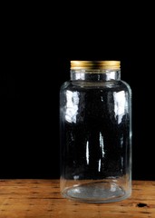Old glass jar with tin lid on black background. 60's.