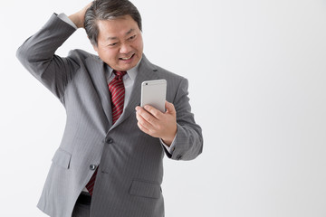 携帯電話を持つビジネスマン、頭をかく、頭を抱える、困る、中年男性
