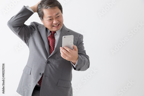携帯電話を持つビジネスマン頭をかく頭を抱える困る中年