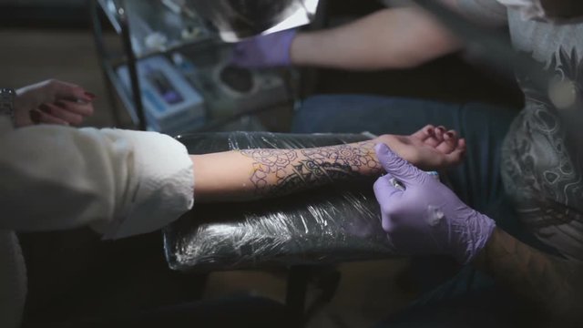 Tattoo master prepares a woman's hand in the process of creating a tattoo close-up