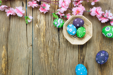 Top view easter background.Happy easter eggs pained on nest also beautiful pink flower.Texture rustic  wooden with decorations and copy space.
