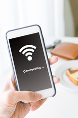 Hand holding smartphone and connecting WiFi network.