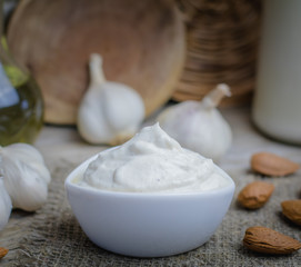 Pine nut mayonnaise or soy almond homemade vegan garlic mayo or bechamel white sauce on rustic rural wooden background.