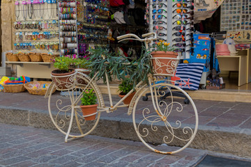 Fototapeta na wymiar Rethymno, Greece - August 2, 2016: Bicycle with flowers in front of souvenir store.