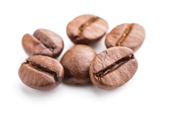 Fototapeta premium roasted coffee beans isolated in white background. Roasted coffee beans background close up. Coffee beans pile from top on white background with copy space for text. Good morning.