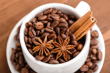 Coffee beans and cinnamon on a background of burlap. Roasted coffee beans background close up. Coffee beans pile from top with copy space for text. Seasoning. Spice. Cinnamon. Badian. Coffee house.